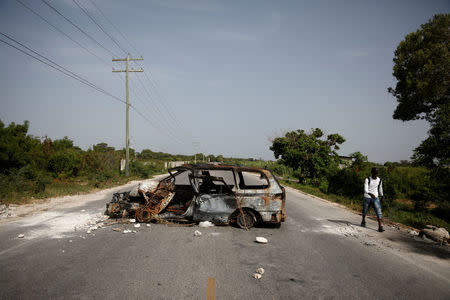 A man walks past a burnt car on the outskirts of Croix-des-Bouquets, Haiti, July 8, 2018. REUTERS/Andres Martinez Casares