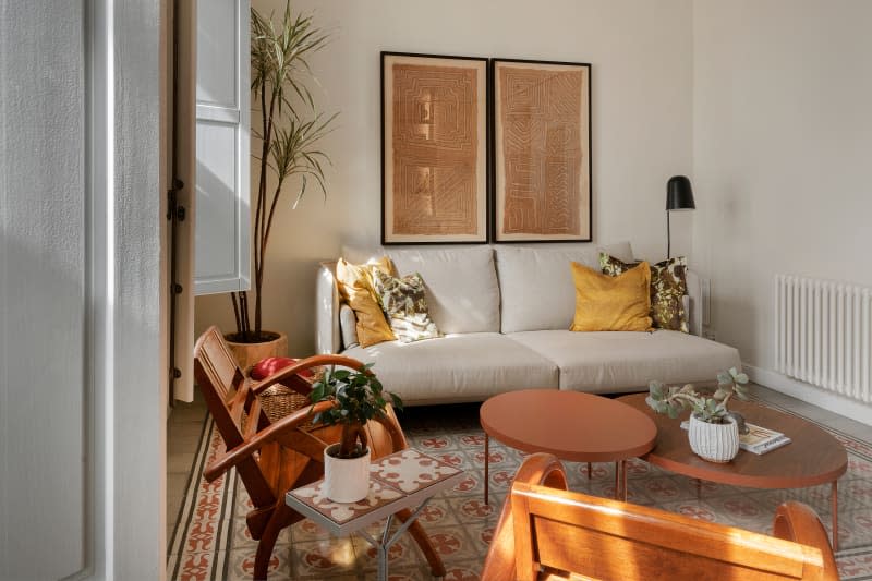 Modern gray sofa, vintage square cross pattern rug, round wood coffee table, textured art on wall