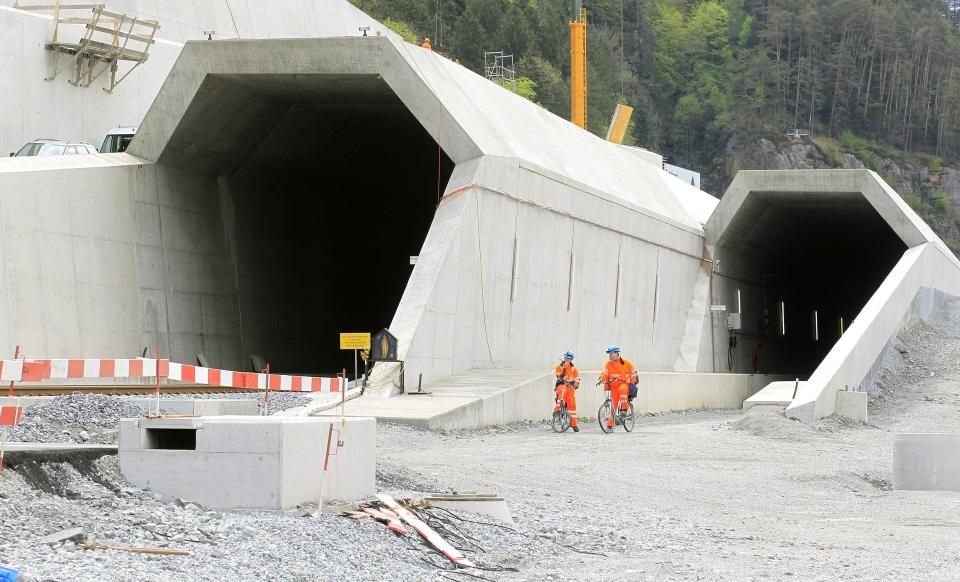 Workers cycle past the northern entrances of the NEAT Gotthard Base tunnel near Erstfeld