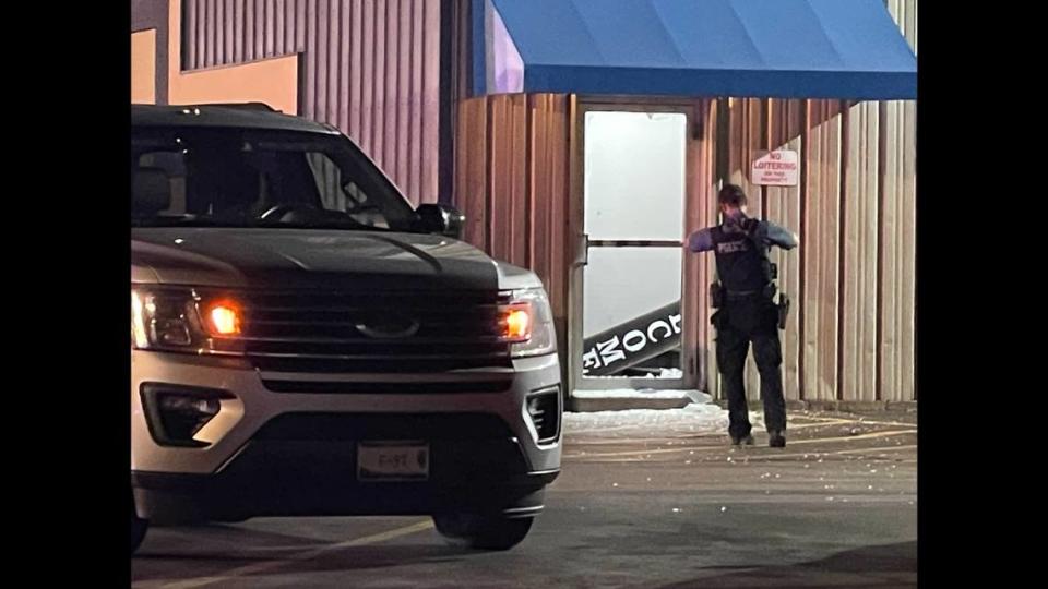 A police officer stands near a shattered glass door after a shooting was reported at St. Clair Bowl in O’Fallon Sunday.