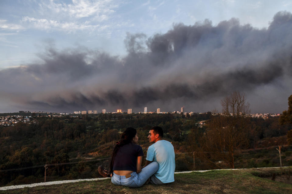 Una pareja charla en un parque mientras el humo causado por los incendios cubre el cielo, en Viña Del Mar, Chile, el 2 de febrero de 2024. (AP Foto/Cristobal Basaure)