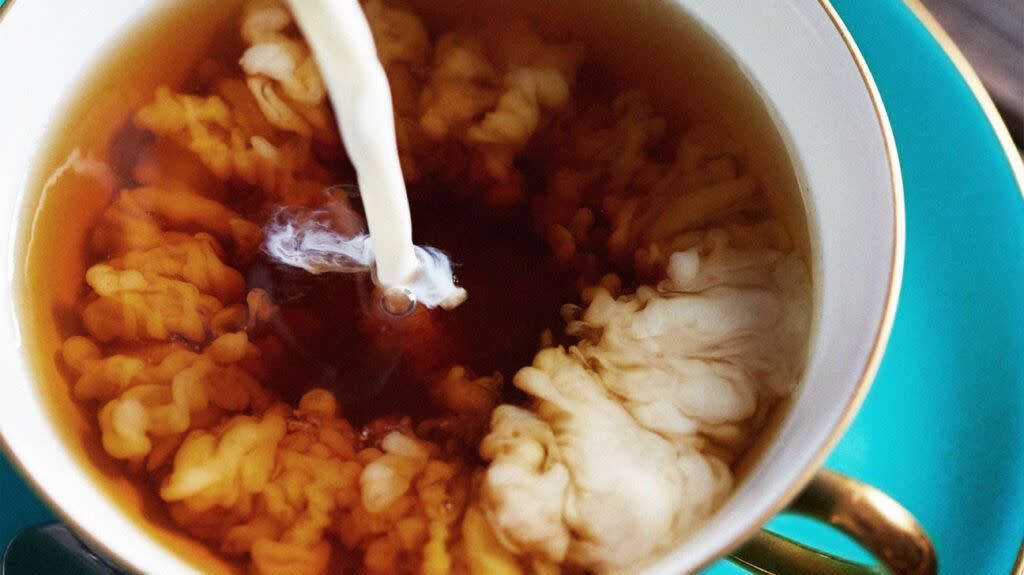 close-up of milk pouring into a cup of coffee