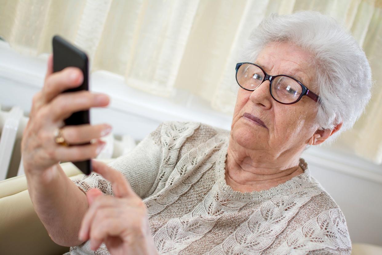 confused old woman using smartphone at home