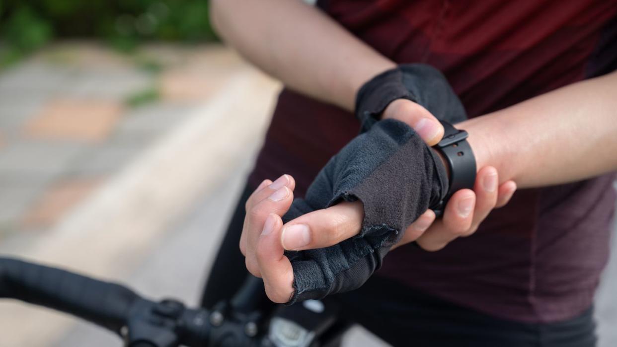 cropped shot of female cyclist holding her wrist caused of wrist pain