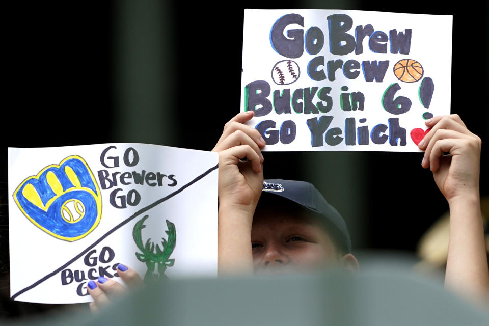 Fans hold signs before a baseball game between the Kansas City Royals and the Milwaukee Brewers, Tuesday, July 20, 2021, in Milwaukee. (AP Photo/Nam Y. Huh)