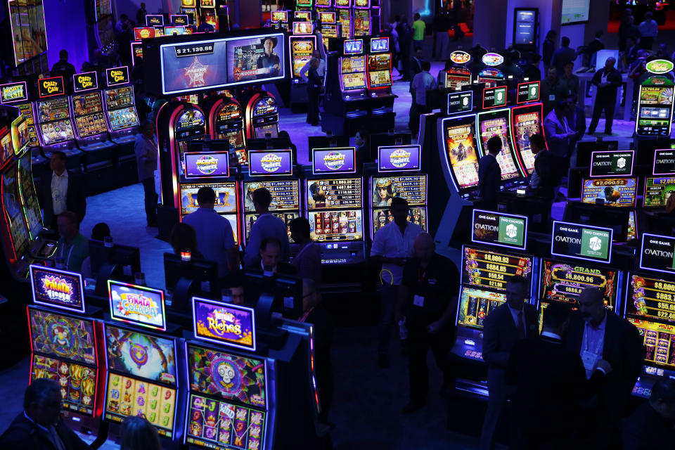 People look at electronic pokie machines in a large darkened room. Source: AP