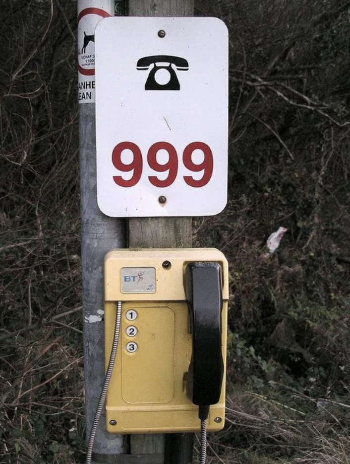 Emergency phone with number '999' above it, attached to a pole for public use