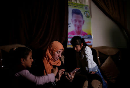 The mother of Mohammed Ayoub, 14, a Palestinian boy who was shot dead by Israeli troops during clashes at the Israel-Gaza border, looks at her son's photos at her house, in the northern Gaza Strip April 21, 2018. REUTERS/Mohammed Salem