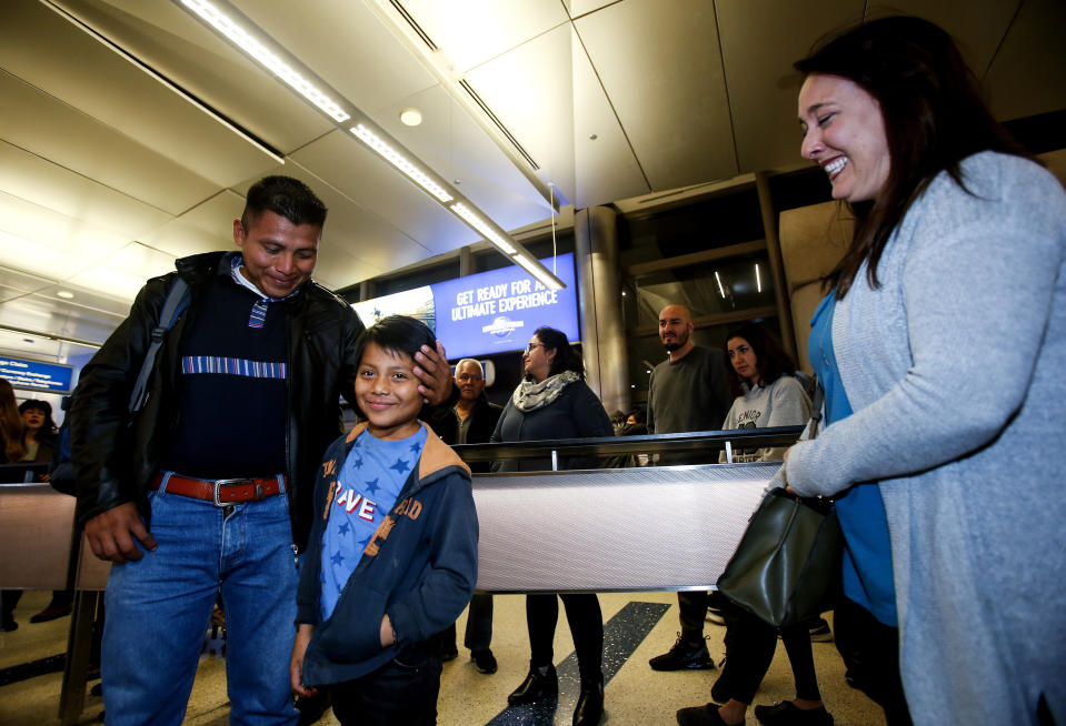 David Xol disfruta del reencuentro con su hijo Byron en el aeropuerto de Los Ángeles el 22 de enero del 2020. Los observa sonriente Holly Sewell (der), quien se hizo cargo de Byron durante varios meses mientras se resolvía la situación de Xol, quien quiere solicitar asilo en EEUU pero había sido deportado antes de poder hacerlo. (AP Photo/Ringo H.W. Chiu)