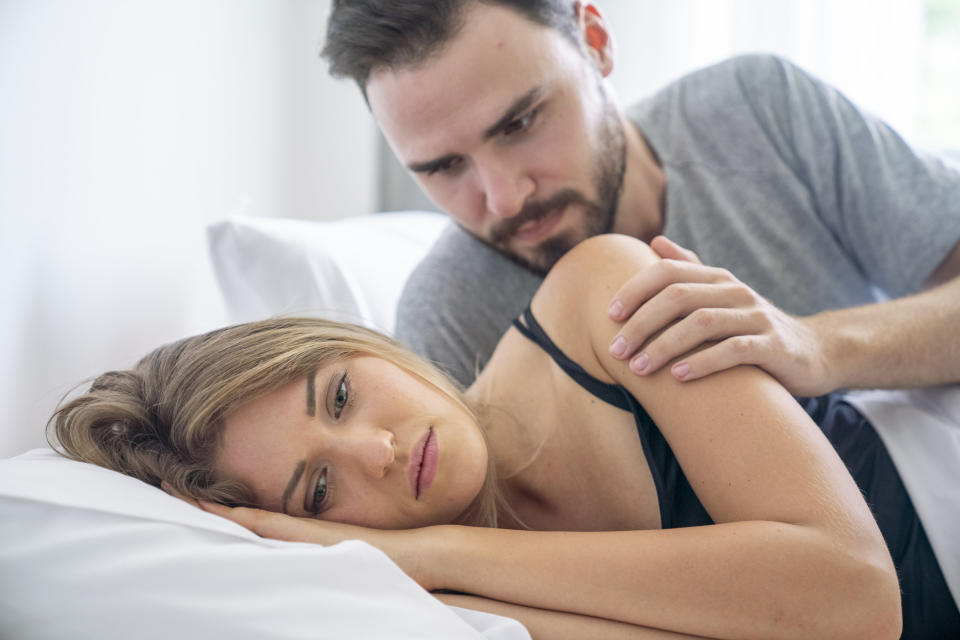 man trying to look over a woman's shoulder in bed