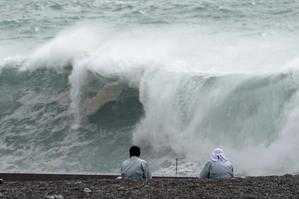 Men look at surging waves as Typhoon Hagibis approaches at a port in town of Kiho, Mie Prefecture, Japan Friday, Oct. 11, 2019. A powerful typhoon is advancing toward the Tokyo area, where torrential rains are expected this weekend. (AP Photo/Toru Hanai)