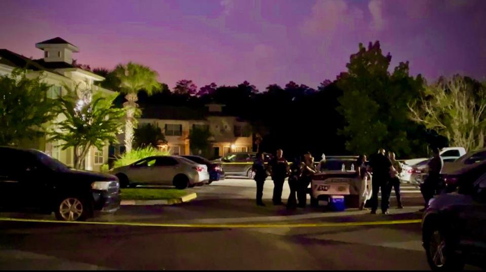 Palm Bay police work the crime scene at The Park apartment complex as lightning flashes along the southwestern edge of the city.