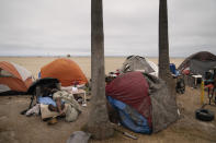 A homeless man naps in an encampment set up along the boardwalk in the Venice neighborhood of Los Angeles, Tuesday, June 29, 2021. The proliferation of homeless encampments on Venice Beach has sparked an outcry from residents and created a political spat among Los Angeles leaders. (AP Photo/Jae C. Hong)