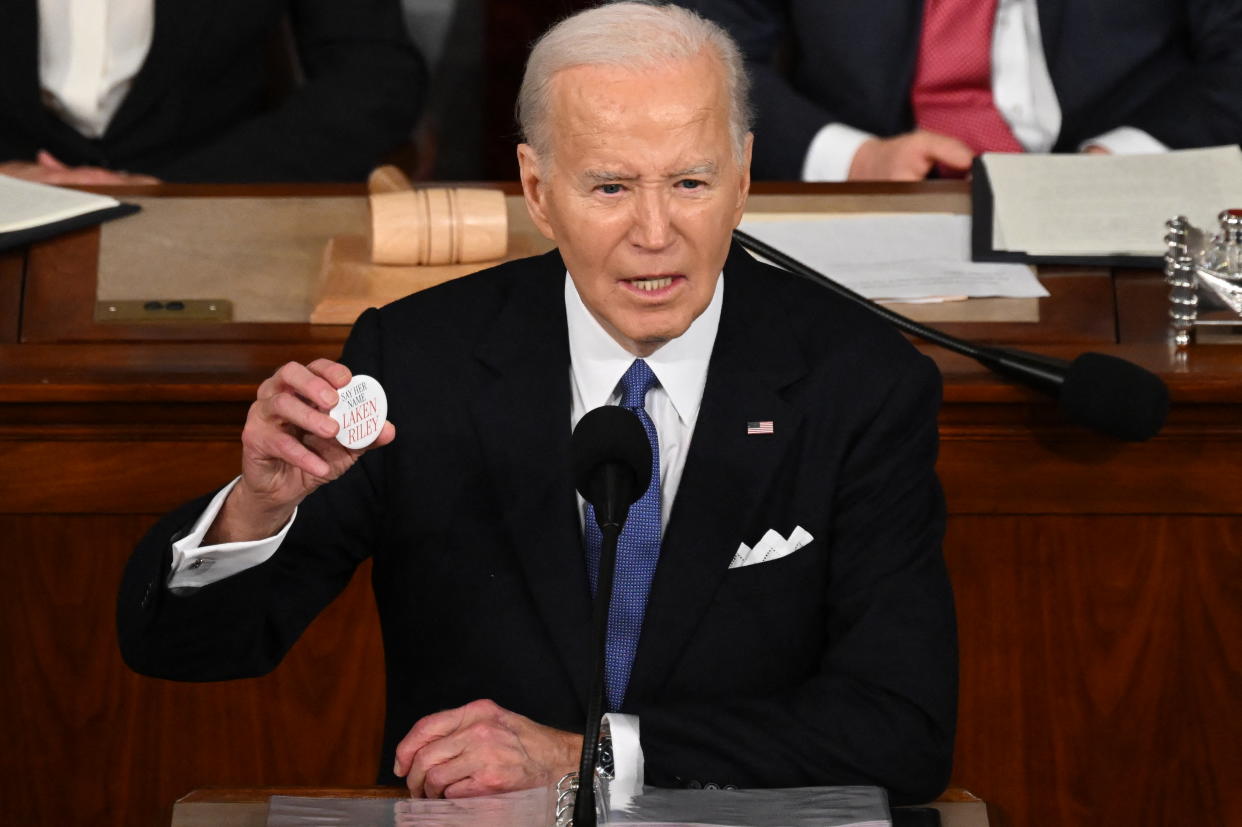 Biden holds up a button in memory of Laken Riley while delivering his State of the Union address.