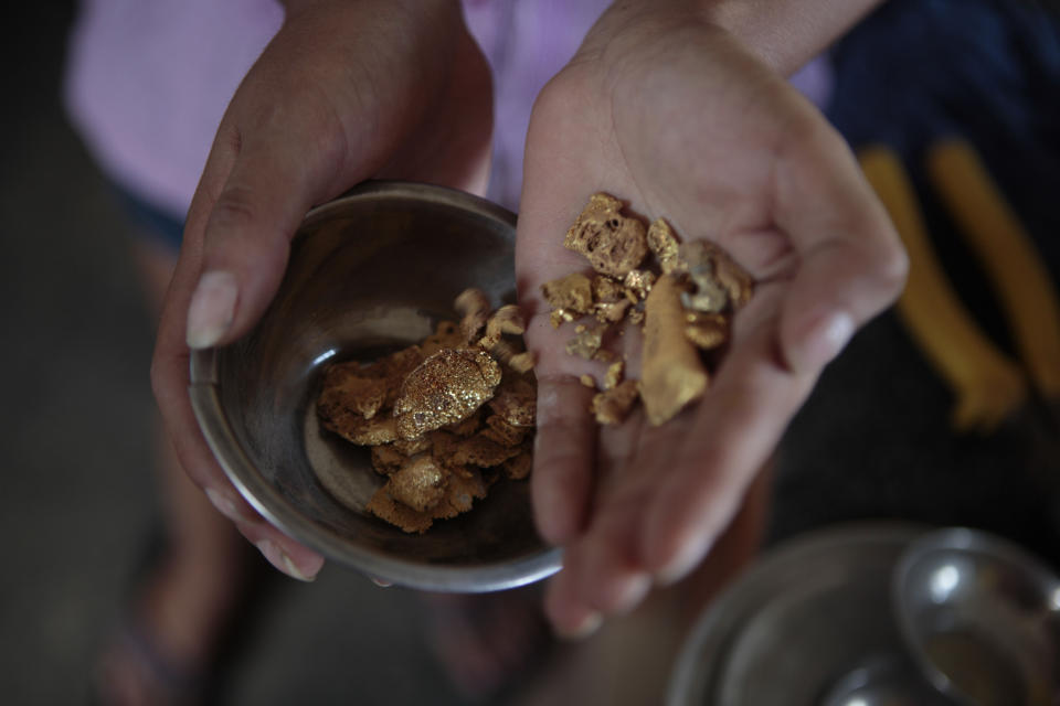 FILE - In this file photo taken on May 20, 2011, an employee shows gold nuggets at a gold-buying store in Puerto Maldonado, Madre de Dios, Peru. The clock has run out for an estimated 40,000 illegal gold miners who had until Saturday to legalize their status in a region of southeastern Peru where fortune-seekers have ravaged rainforests and contaminated rivers. The miners already have been clashing with police while intermittently blocking traffic on the commercially vital interoceanic highway that links the Pacific coast with Brazil. (AP Photo/Esteban Felix,File)