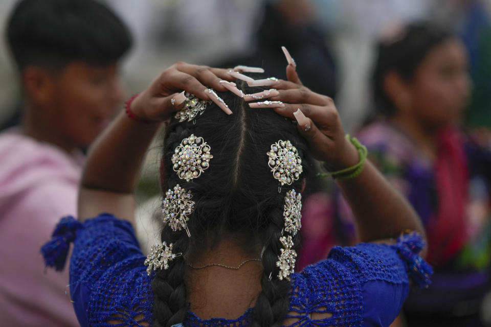 A Purepecha Indigenous woman adjusts her hair after arriving to Ocumicho, having walked from Erongaricuaro with a group carrying a flame that the community had kept alive for one year, in Michoacan state, Mexico, Wednesday, Jan. 31, 2024. A new flame will be lit in Ocumicho at the “New Fire” ceremony on Feb. 2 to mark the new year, after extinguishing the old fire on Feb. 1 which is considered an orphan day that belongs to no month and is used for mourning and renewal. (AP Photo/Eduardo Verdugo)