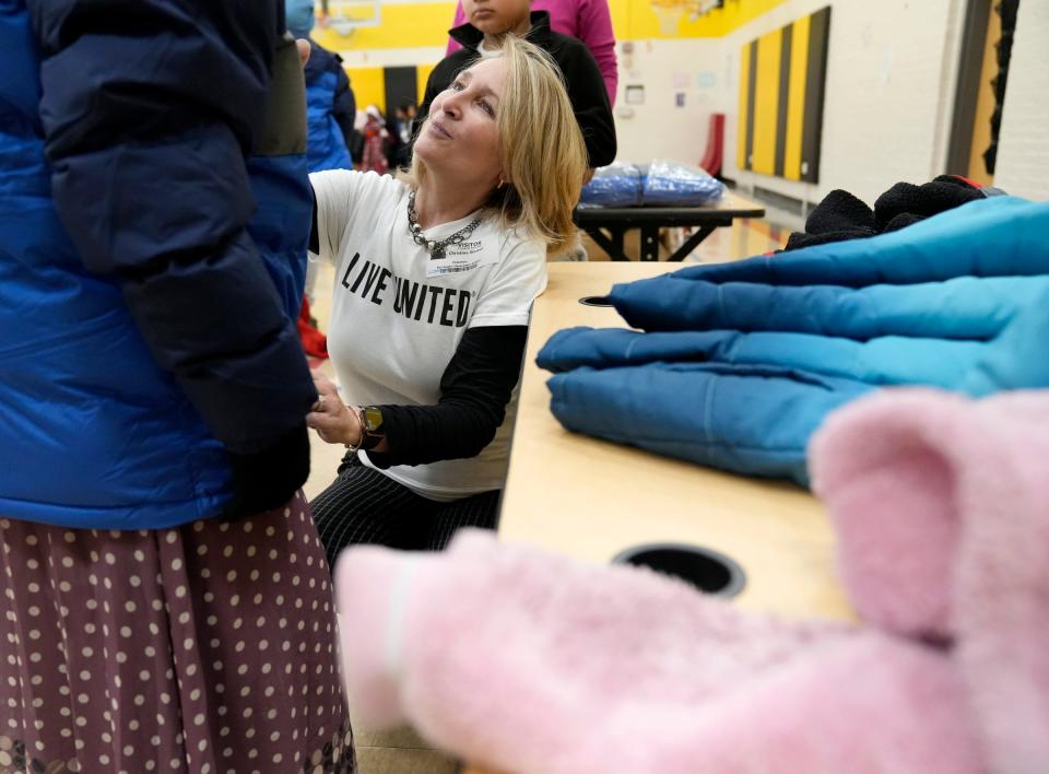 Tina Starner, United Way's Success by Third Grade administrative coordinator, helps a child try on winter coats during a distribution event at Burroughs Elementary School on Wednesday.