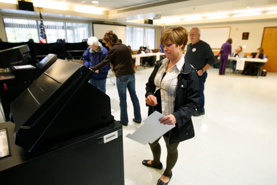 Joyce Bisbo feeds her ballot into the ballot machine at Barnard Fire House in Greece in this file photo from 2014. Behind her is election inspector Jim Cook and Suzanne Mrzywka, who was helping Shirley Carey.