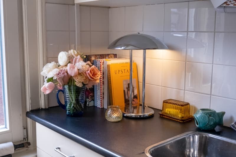 Floral arrangement next to cooking book in a kitchen.