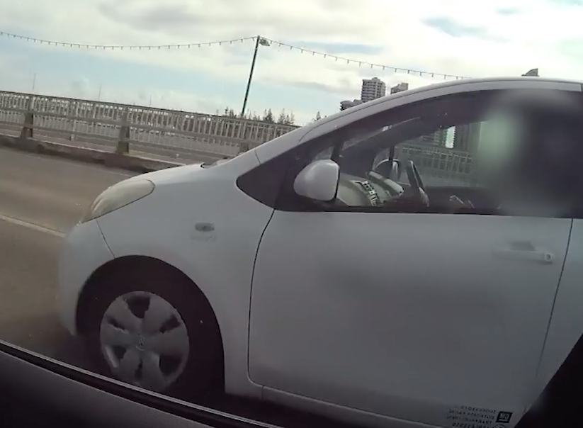 A female driver shown using her phone while driving over a bridge. Source: QLD Police