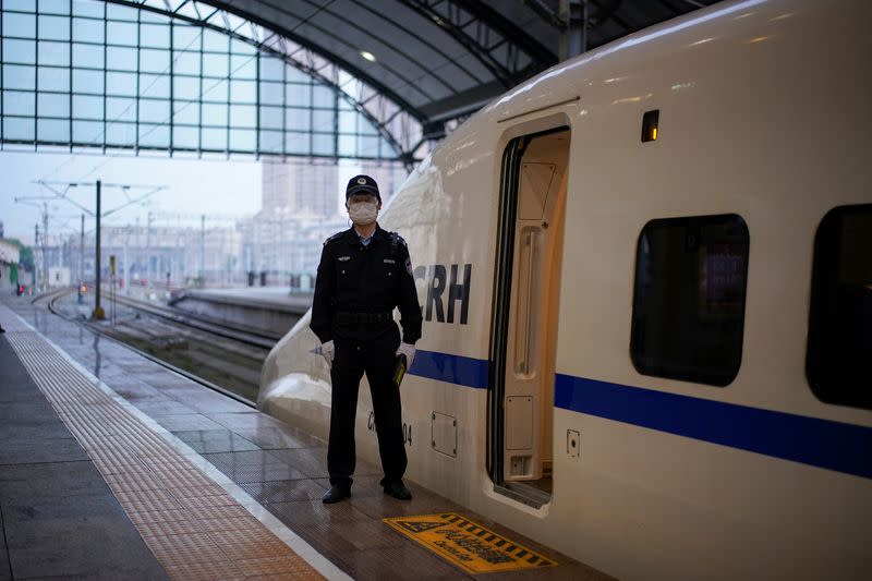 A policeman stands beside a high-speed train, which is the first train to leave Hankou Railway Station in Wuhan