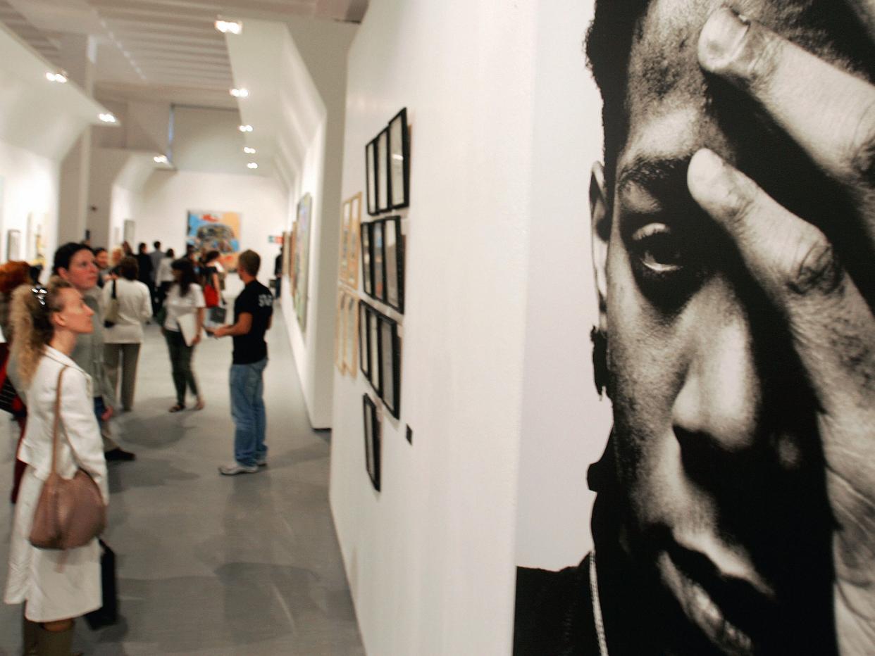 Picture of people looking at a Basquiat portrait in a museum.