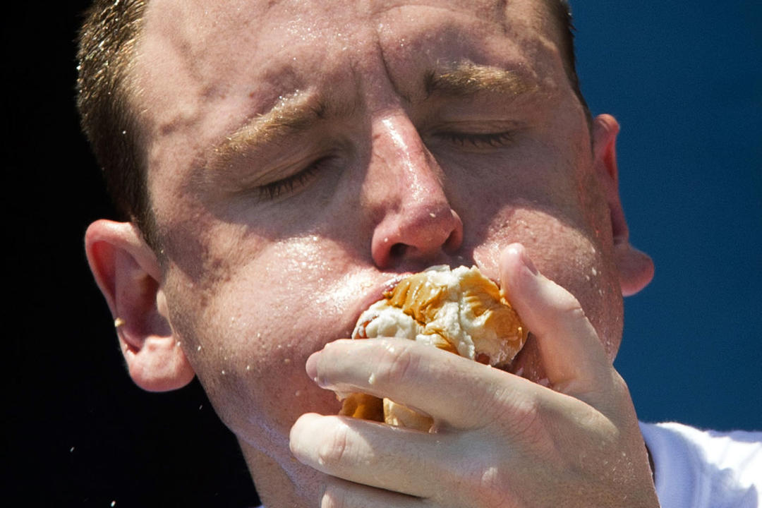 FILE - Five-time reigning champion Joey Chestnut competes in the Nathan's Famous Hot Dog Eating World Championship on July 4, 2012, in the Coney Island section of the Brooklyn borough of New York. The annual Nathan's Famous Fourth of July hot dog eating contest will see a group of competitive eaters wolf down as many franks as possible in New York City on Thursday, July 4, 2024 — but this year, the event's biggest star, Chestnut, will be eating from 1,900 miles (3,000 km) away. (AP Photo/John Minchillo, File)