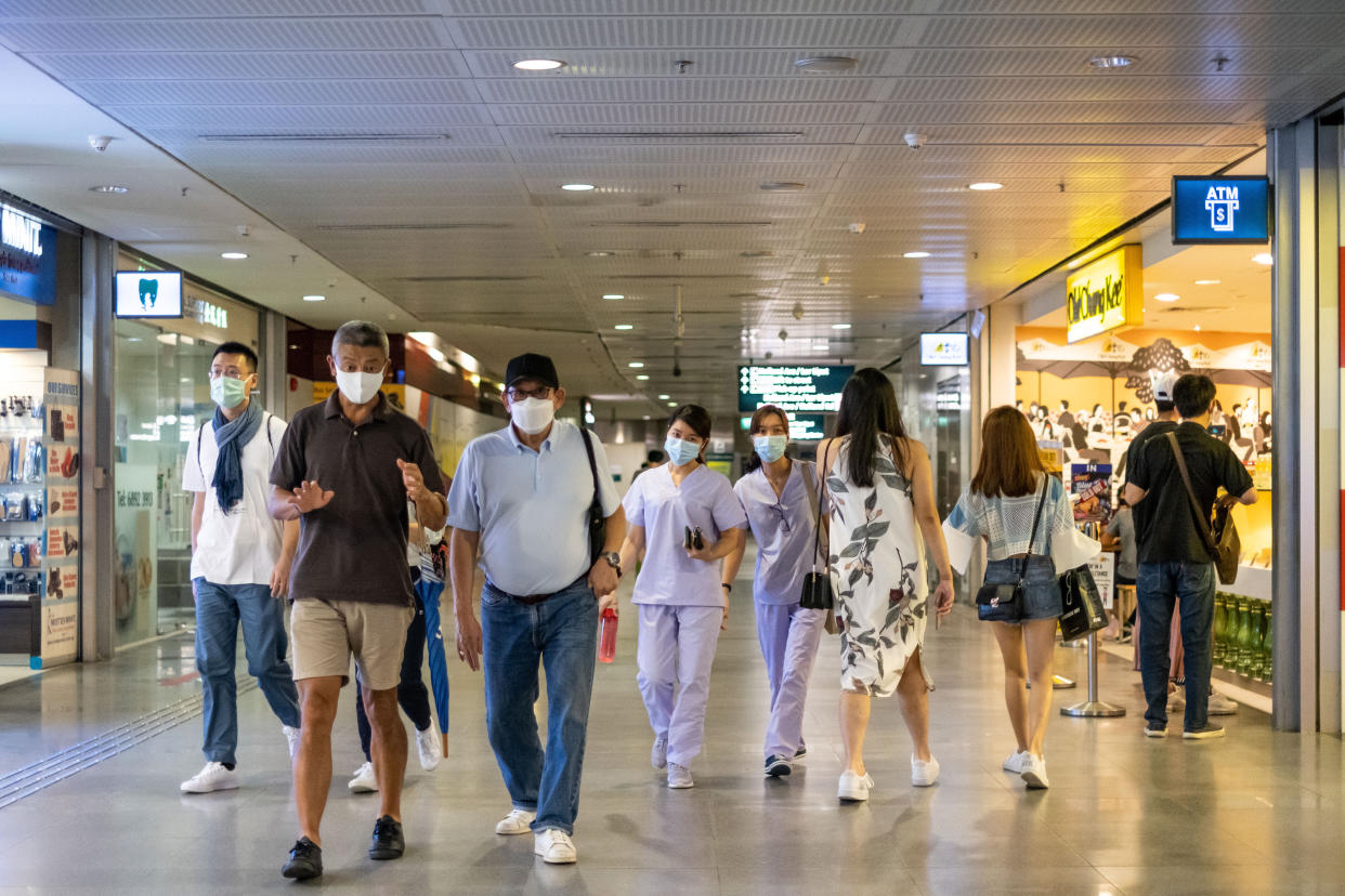 People wearing face masks walking along an MRT train station in Singapore.