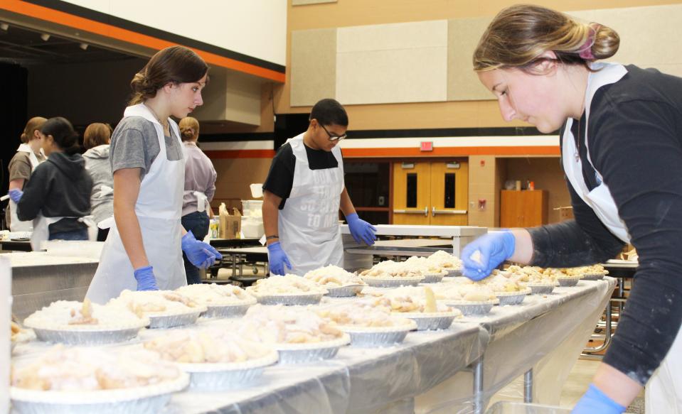 Music students Caroline Hughes, Dominic Brown and Cora Taylor add toppings to filled crusts.