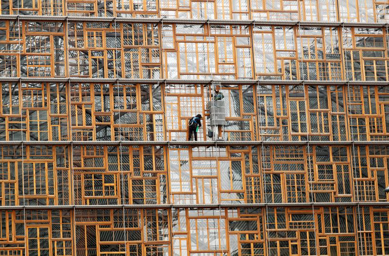 FILE PHOTO: Window cleaners work on the facade of the European Union Council building in Brussels