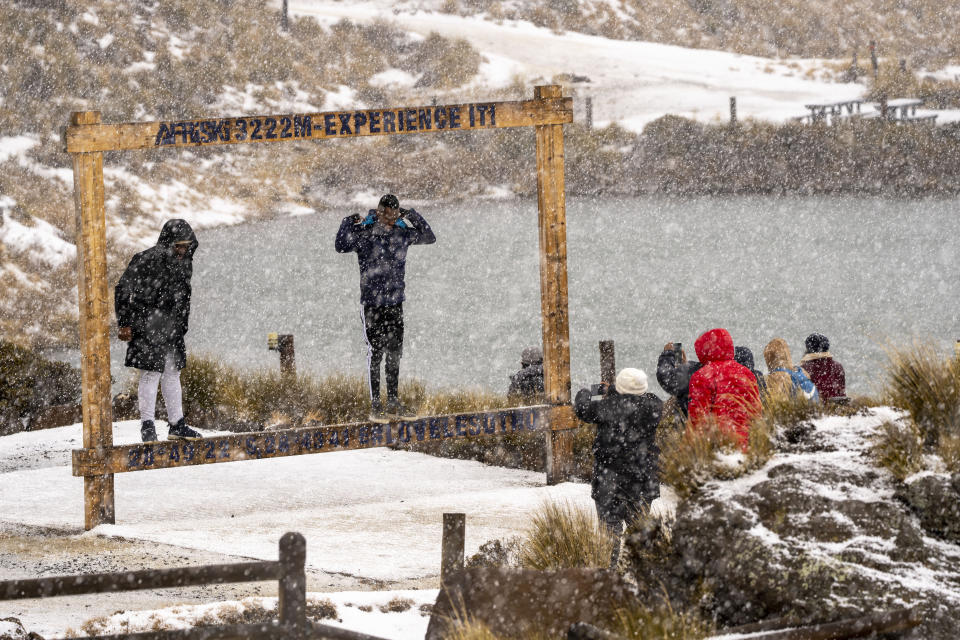 Visitors have their picture taken as snow falls at the Afriski ski resort near Butha-Buthe, Lesotho, Saturday July 30, 2022. While millions across Europe sweat through a summer of record-breaking heat, Afriski in the Maluti Mountains is Africa's only operating ski resort south of the equator. It draws people from neighboring South Africa and further afield by offering a unique experience to go skiing in southern Africa. (AP Photo/Jerome Delay)