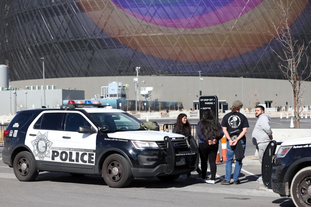 People are seen in handcuffs near the Sphere after law enforcement responded to reports that anti-abortion activist Maison Des Champs (not pictured) had climbed to the top of the structure on Feb. 7, 2024, in Las Vegas, Nevada. DesChamps was previously arrested for also climbing the Aria in August 2021.