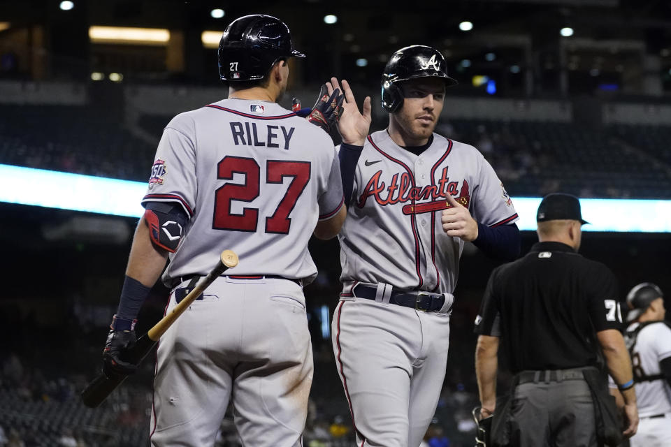 Atlanta Braves' Freddie Freeman high fives Austin Riley (27) after scoring on a double hit by Ozzie Albies during the fifth inning of a baseball game against the Arizona Diamondbacks, Monday, Sept. 20, 2021, in Phoenix. (AP Photo/Matt York)