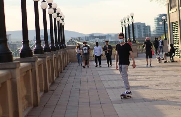 A skateboarder wearing a mask makes his way along the pathway next to the Château Laurier hotel in Ottawa on May 15, 2021. (Trevor Pritchard/CBC - image credit)