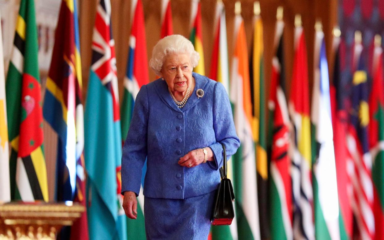 The Queen walks past Commonwealth flags in St George's Hall at Windsor Castle - PA