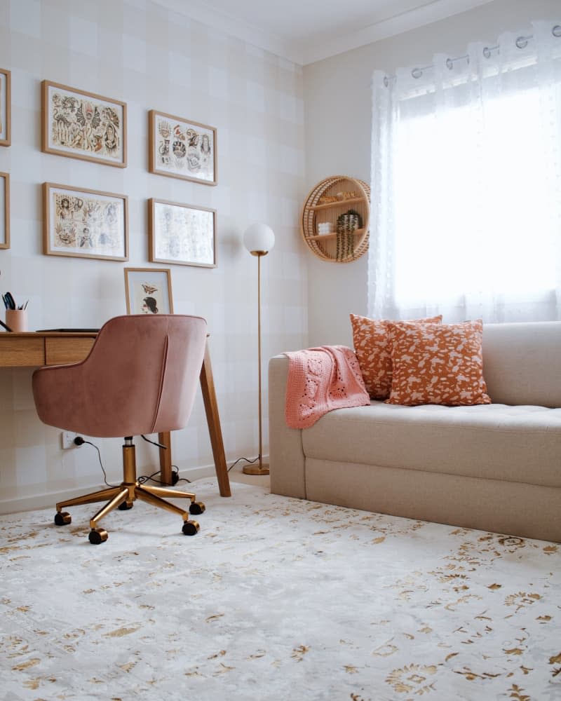 office with beige and white gingham walls, wood desk, and gray sofa