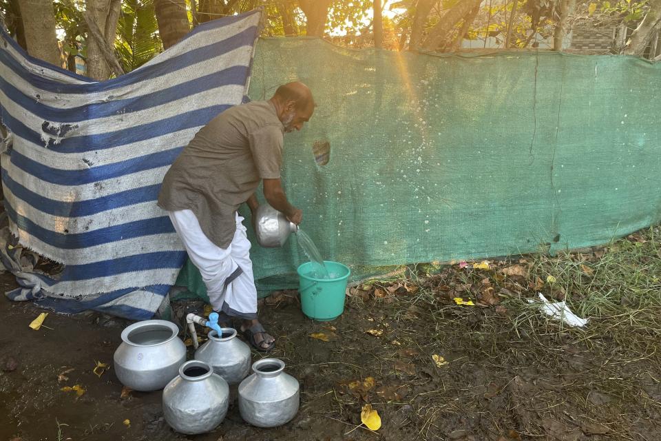 A man collects water in different buckets and pots in Kochi, Kerala state, India on March 1, 2023. There are about 100 families dependent on this single tap for clean water. (Uzmi Athar/Press Trust of India via AP)