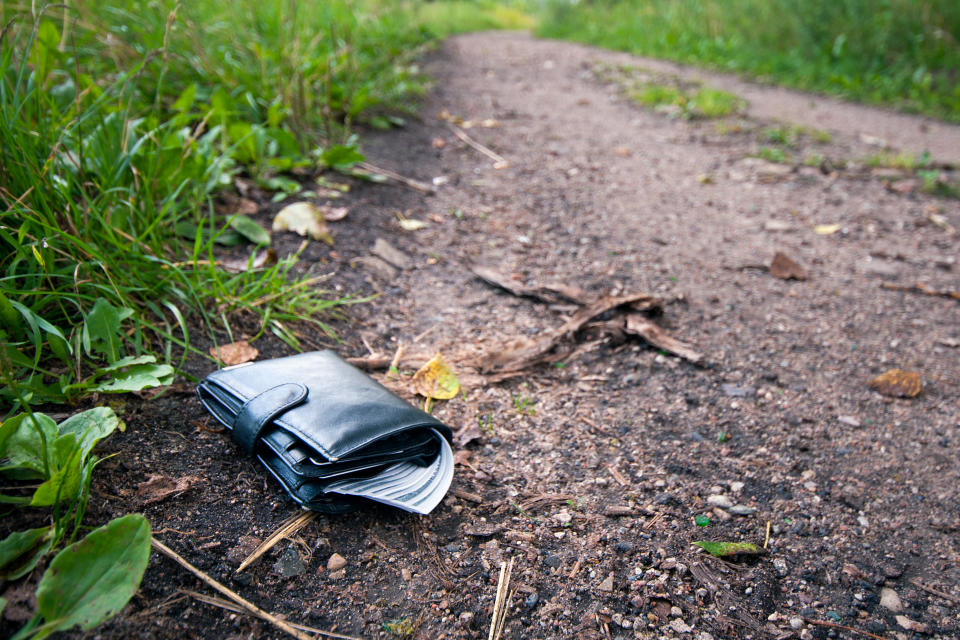 A file picture of a black leather wallet on a path.