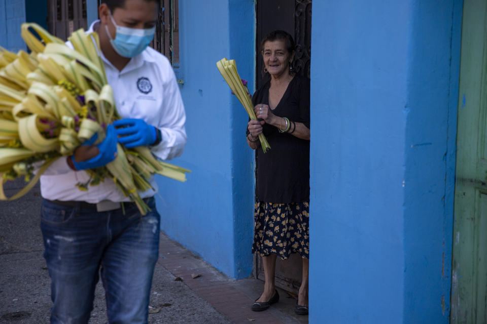 A woman smiles after receiving a palm frond from a Cristo Rey brotherhood member during Palm Sunday in Guatemala City, April 5, 2020. (AP Photo/Moises Castillo)