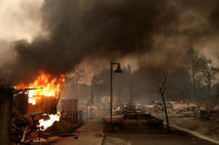 <p>Burned out cars sit next to a building on fire in a fire ravaged neighborhood on Oct. 9, 2017 in Santa Rosa, Calif. (Photo: Justin Sullivan/Getty Images) </p>