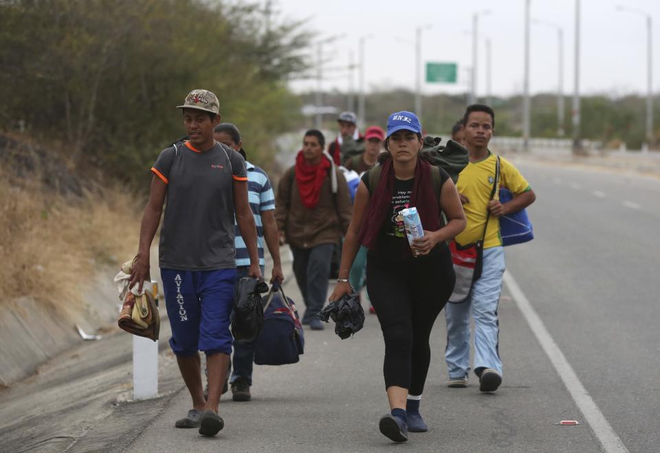 Venezuelan migrants walk on the Pan-American Highway, after crossing the border Peru - Ecuador border, in Tumbes, Peru, Friday, June 14, 2019. Venezuelan citizens are rushing to enter Peru before the implementation of new entry requirements on migrants fleeing the crisis-wracked South American nation. (AP Photo/Martin Mejia)