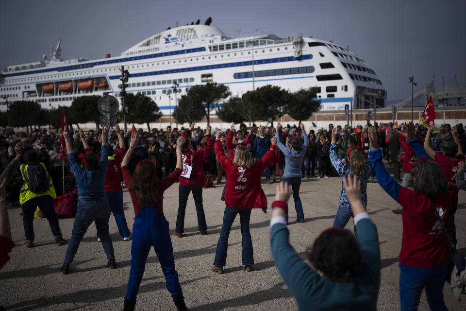 Protesters perform a dance during a demonstration in Marseille, southern France, Tuesday, March 7, 2023. Garbage collectors, utility workers and train drivers are among people walking off the job Tuesday across France. They are expressing anger at a bill raising the retirement age to 64, which unions see as a broader threat to the French social model. (AP Photo/Daniel Cole)