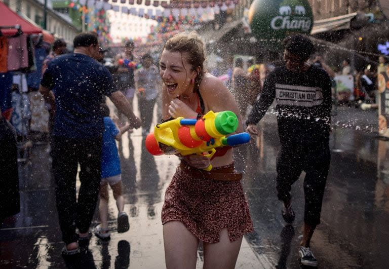 Una mujer corre por la calle mientras los turistas participan en una batalla de agua, en la calle Khao San en vísperas del Año Nuevo tailandés, conocido localmente como Songkran, en Bangkok el 12 de abril de 2023