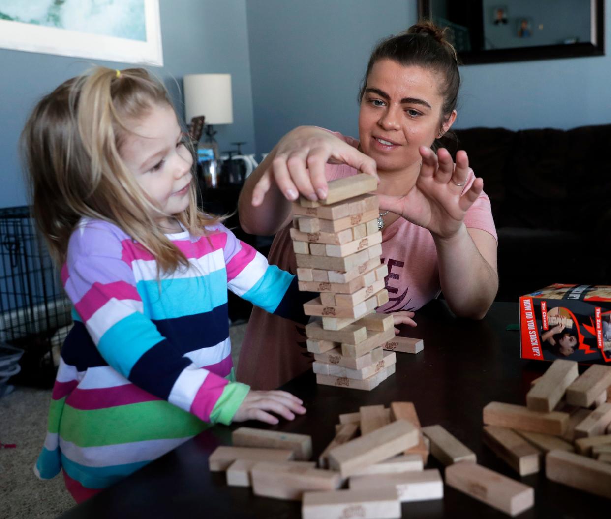 Cheri Branham plays Jenga with her youngest daughter, 3, in their home in Howard, Wis.