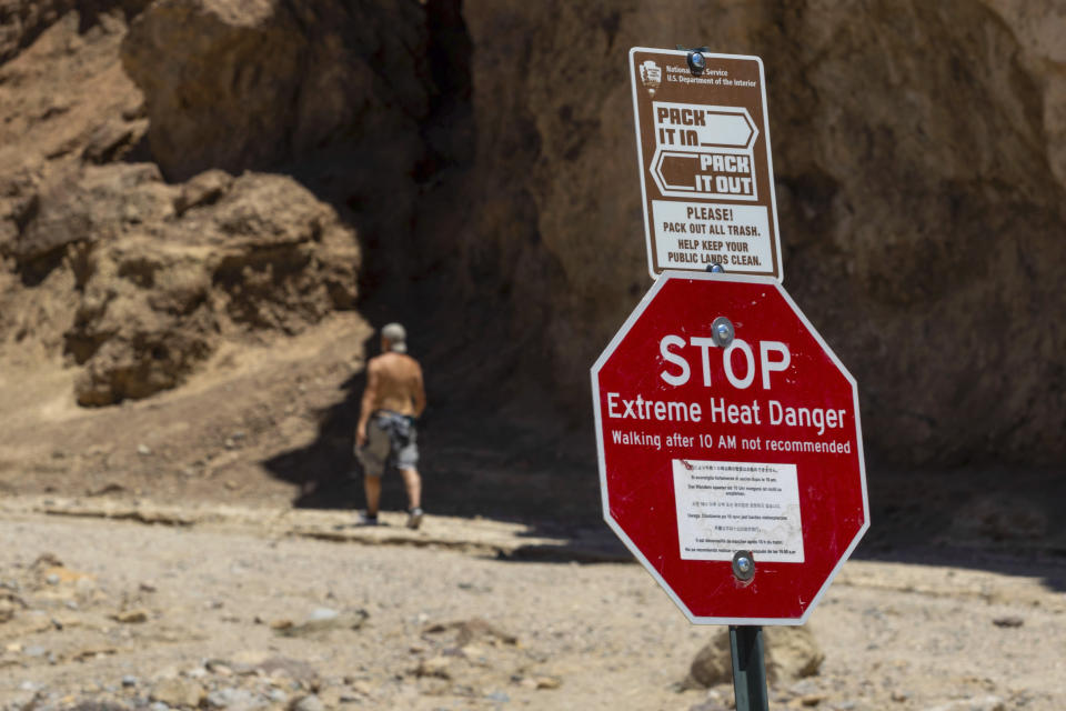 A hiker passes a sign warning hikers of extreme heat at the start of the Golden Canyon trail on July 11, 2023, in Death Valley National Park, Calif. A 71-year-old Los Angeles-area man died at the trailhead on Tuesday, July 18, as temperatures reached 121 degrees (49 Celsius) or higher and rangers suspect heat was a factor, the National Park Service said in a statement Wednesday. (AP Photo/Ty ONeil)