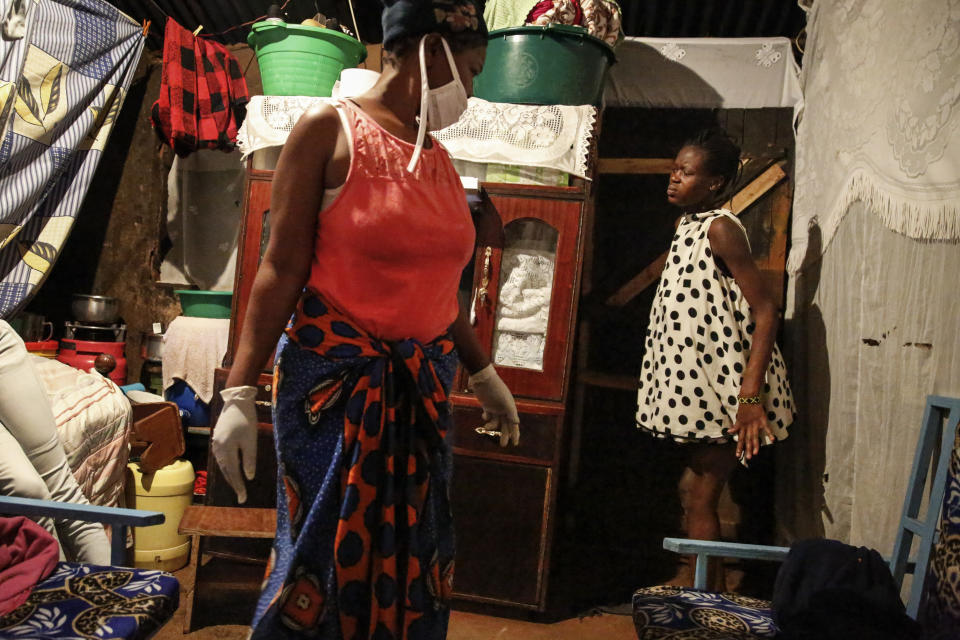 Traditional birth attendant Emily Owino, left, prepares to help Veronica Atieno, right, deliver her baby in Emily's one-room house during a dusk-to-dawn curfew, in the Kibera slum of Nairobi, Kenya in the early hours of Friday, May 29, 2020. Kenya already had one of the worst maternal mortality rates in the world, and though data are not yet available on the effects of the curfew aimed at curbing the spread of the coronavirus, experts believe the number of women and babies who die in childbirth has increased significantly since it was imposed mid-March. (AP Photo/Brian Inganga)