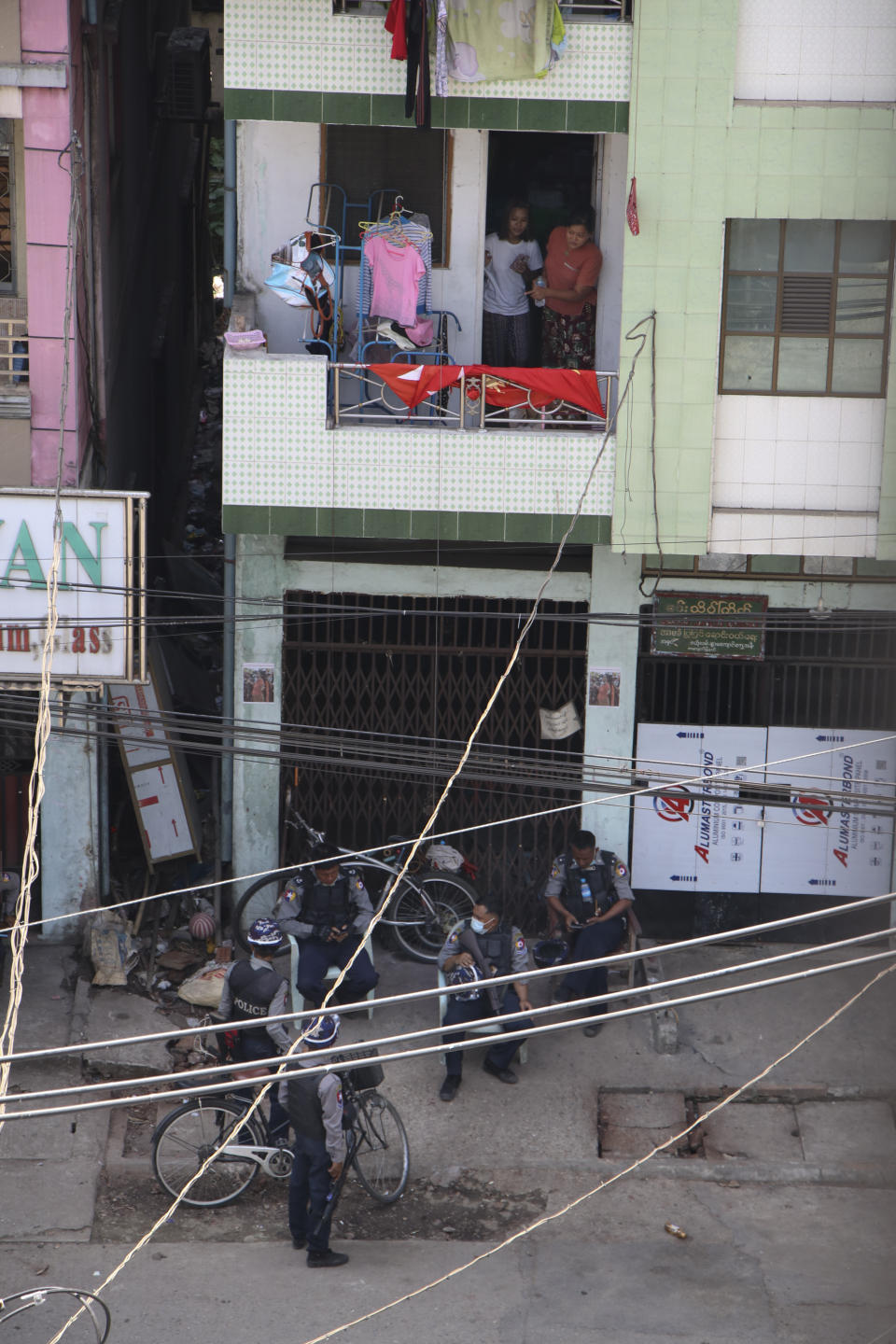 Residents look at policemen resting below their home in Yangon, Myanmar, Friday, March 19, 2021. Authorities in Myanmar arrested a spokesman for ousted leader Aung San Suu Kyi’s political party as they intensify efforts to choke off the spread of information about growing protests against last month’s military takeover. (AP Photos)