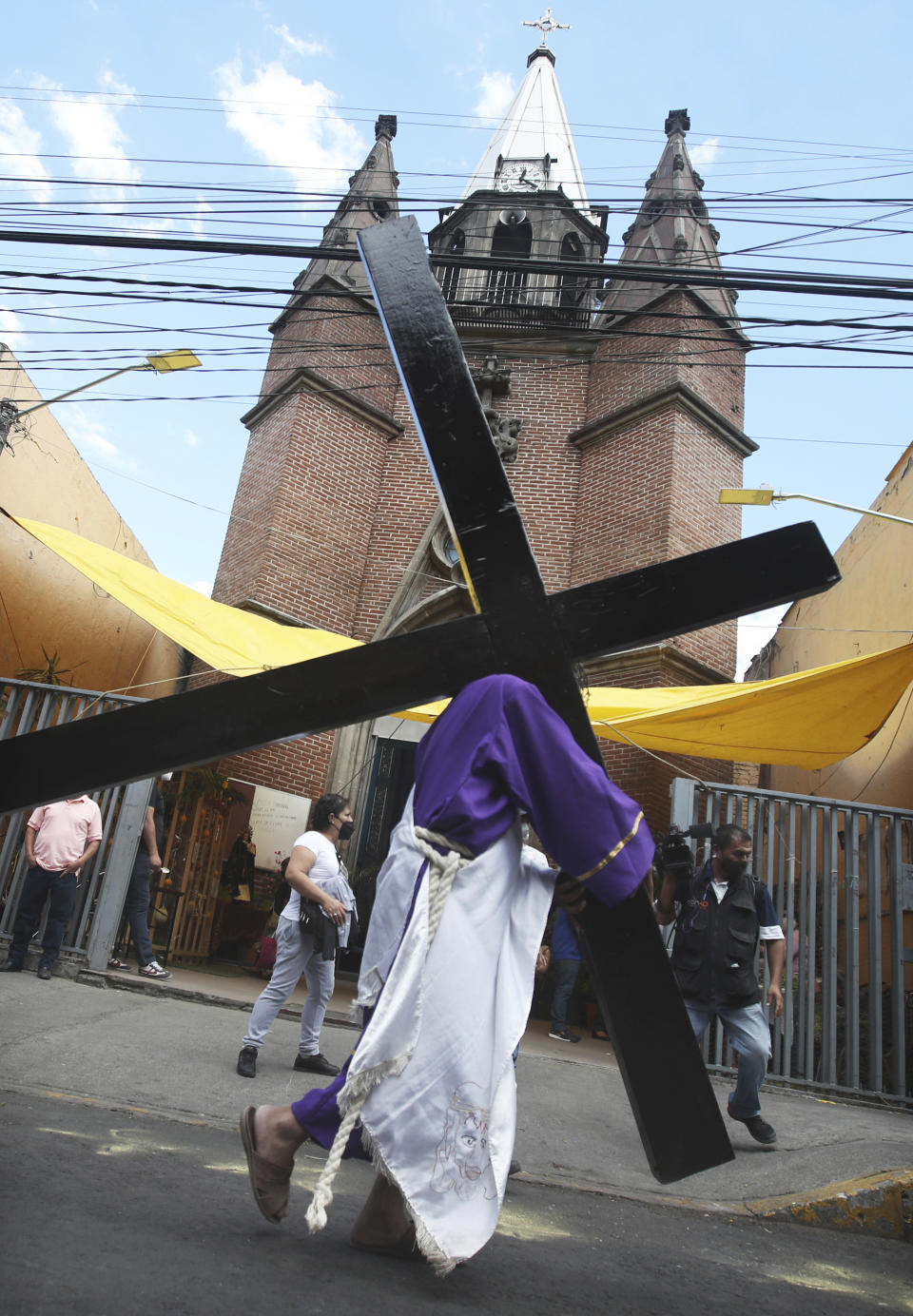 A Christian carries a cross in a reenactment of the crucifixion of Jesus Christ, in the Iztapalapa borough of Mexico City, Friday, April 2, 2021, amid the new coronavirus pandemic. Christians in Latin America mark Good Friday this year amid the coronavirus crisis with some religious sites open to limited numbers of faithful but none of the mass pilgrimages usually seen in the Holy Week leading up to Easter. (AP Photo/Marco Ugarte)