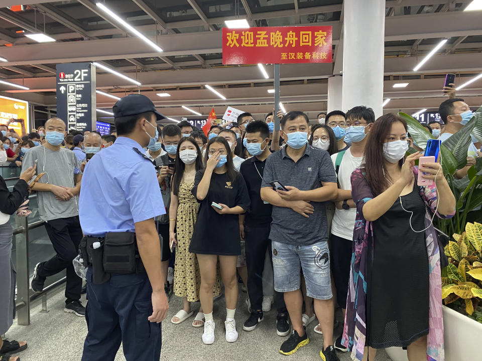 Police stand guard as supporters of Huawei CFO Meng Wanzhou gather at Shenzhen Bao'an International Airport in Shenzhen in southern China's Guangdong Province, Saturday, Sept. 25, 2021. China's government was eagerly anticipating the return of a top executive from global communications giant Huawei Technologies on Saturday following what amounted to a high-stakes prisoner swap with Canada and the U.S. (AP Photo/Ng Han Guan)