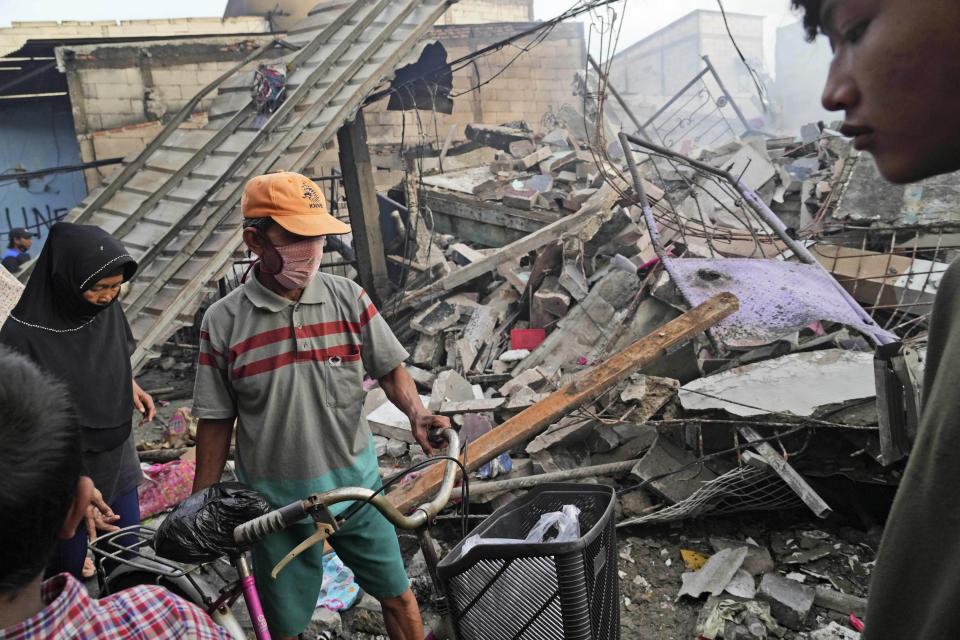 People inspect the damage at their neighborhood following a fuel depot fire in Jakarta, Indonesia, Saturday, March 4, 2023. A large fire broke out at the fuel storage depot in Indonesia's capital Friday, killing multiple people, injuring dozens of others and forcing the evacuation of thousands of nearby residents after spreading to their neighborhood, officials said. (AP Photo/Tatan Syuflana)